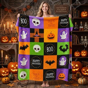 Puede incluir: Una manta de felpa con temática de Halloween que presenta un patrón de cuadrícula de cuadrados morados, naranjas, verdes y negros. El diseño incluye ilustraciones de fantasmas, calaveras, murciélagos, calabazas y el texto BOO, TRICK OR TREAT, HAPPY HALLOWEEN.