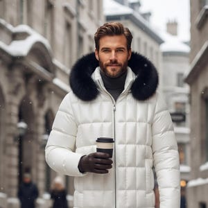 Puede incluir: Una chaqueta acolchada blanca con capucha ribeteada en piel negra, sobre un suéter de cuello alto gris oscuro. El conjunto incluye pantalones vaqueros azul oscuro, guantes de cuero marrón y botas de cuero marrón con cordones y café.