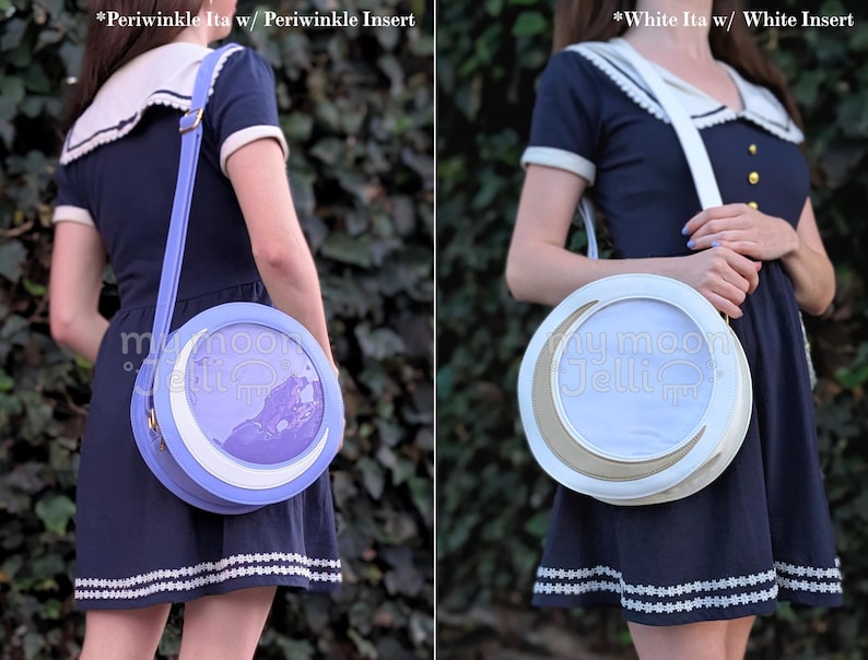 May include: Two round crossbody bags with a crescent moon design. The bag on the left is periwinkle blue with a periwinkle blue insert. The bag on the right is white with a white insert. Both bags have a white strap.
