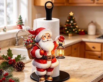 May include: A paper towel holder featuring a Santa Claus figure wearing a red and white suit, holding a lit lantern in one hand and carrying a basket of greenery on the back. The holder has a black circular base and a black vertical handle.