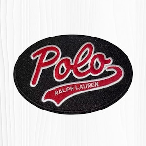 May include: An oval-shaped black embroidered patch featuring the word Polo in red script with a white outline. Below the word Polo, the text Ralph Lauren is embroidered in white capital letters on a red swoosh background.
