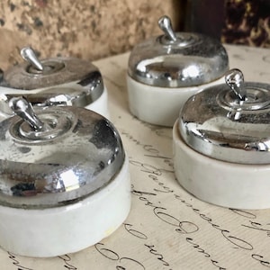 Peut inclure: Quatre interrupteurs vintage en porcelaine avec des boutons basculants chromés. Les couvercles sont blancs avec une finition chromée brillante.