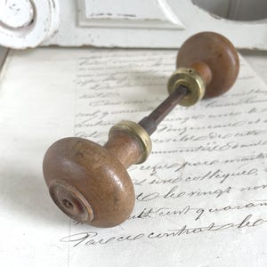 Peut inclure: Un bouton de porte en bois vintage avec un design rond classique. Le bouton est en bois brun clair, orné d'éléments en laiton. Le bouton de porte est de style traditionnel, parfait pour ajouter une touche de charme antique à n'importe quelle porte.