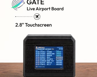 May include: A black digital device labeled GATE Live Airport Board with a 2.8" touchscreen displaying a flight arrivals schedule for Frankfurt Am Main, including flight numbers, origin cities, and status updates like landed and inbound.