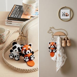 May include: Two felt animal keychains, one panda and one red panda, attached to a cream-coloured bag. A gold-toned wire wall hook shaped like a fox holds a red panda keychain, a patterned muslin cloth, and a pair of small beige leather shoes.