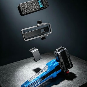 May include: A disassembled blue and black electronic device with a textured top panel featuring a small digital screen, a rectangular silver frame, a black bracket, and a main handle component with a clear plastic casing and internal details.