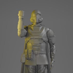Puede incluir: Una figura gris monocromática de un soldado blindado de pie con casco y capa. La figura está posada con un brazo levantado en un puño, con una armadura de pecho detallada, bolsas utilitarias en la cintura y placas de pierna texturizadas.