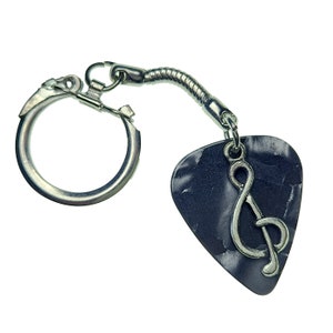 May include: A guitar pick keychain with a silver treble clef charm. The pick is dark blue with a marbled effect. The keychain has a silver key ring and a flexible metal connector.