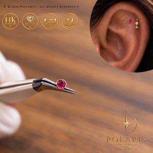 May include: A 14K gold flat back stud earring featuring a round, cabochon-cut pink gemstone. The earring is held by metal tweezers, with an inset showing the stud worn in an ear cartilage piercing alongside a small pearl and diamond dangle.