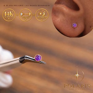 May include: A 14K gold threadless push-pin stud earring featuring a round, purple cabochon stone. The jewelry is shown held by tweezers and worn in an earlobe, with icons indicating 14K gold, threadless design, and 24/7 wear capability.