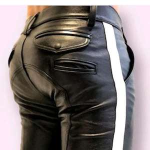 May include: Black leather trousers featuring a prominent vertical white stripe running down the side. The trousers include a rear pocket with a flap and a button closure, a secondary horizontal slit pocket, belt loops, and visible seam detailing.