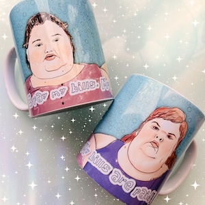 Puede incluir: Dos tazas de cerámica blanca con retratos ilustrados de una persona sobre un fondo azul claro con patrón de burbujas. Una taza muestra el texto I pay my bills, y la otra muestra el texto My bills are paid, ambos en letras blancas.
