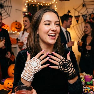 May include: A pair of fingerless gloves featuring a crocheted spider web pattern, with one glove in white and the other in black. The gloves are designed to cover the back of the hand and wrap around the fingers, showcasing a detailed web design.