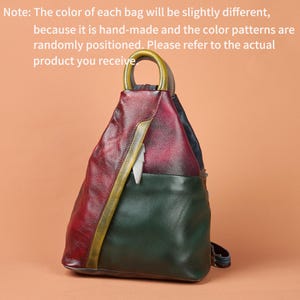 Puede incluir: Una mochila multicolor con superficie texturizada que presenta paneles en rojo oscuro, verde bosque y detalles amarillos. Incluye un asa superior redondeada, cierre de cremallera y un pequeño dije en forma de pluma blanca. El texto dice: Note: The color of each bag will be slightly different, because it is hand-made and the color patterns are randomly positioned. Please refer to the actual product you receive.