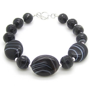 Puede incluir: Pulsera de &aacute;gata negra y blanca con cierre de plata. La pulsera presenta cuentas redondas y ovaladas con un patr&oacute;n rayado.