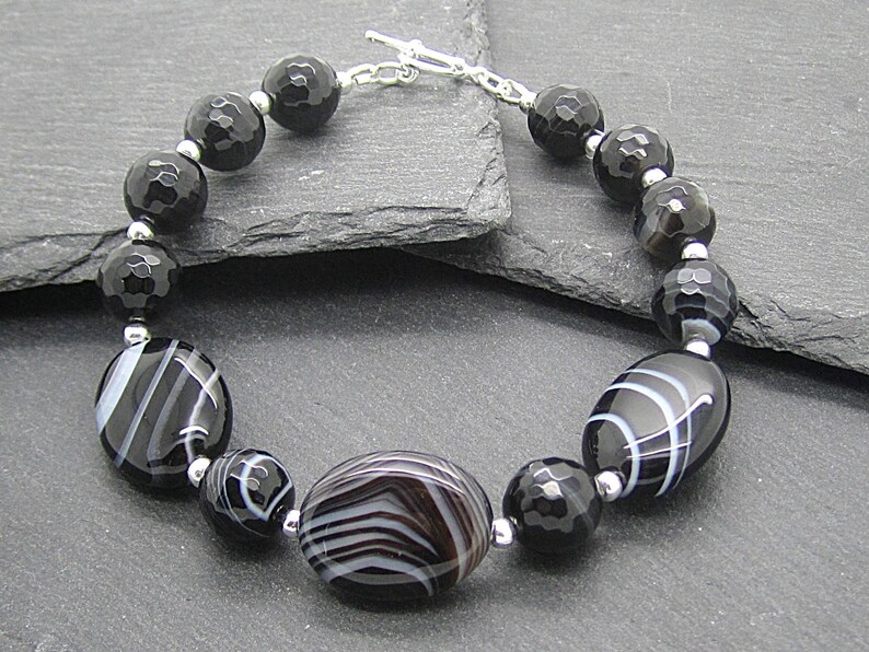 Puede incluir: Pulsera de &aacute;gata negra y blanca con cierre de plata. La pulsera presenta cuentas ovaladas con rayas blancas y cuentas redondas facetadas.