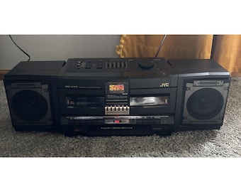 May include: A black JVC PC-V77 portable stereo system featuring dual cassette decks, a central digital radio tuner display showing 104.1, a graphic equaliser, and two detachable side speakers with Hyper-Bass Sound branding.