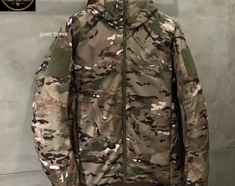Peut inclure: Une veste à capuche avec un motif camouflage multicolore dans des tons marron, vert et beige. La veste présente une fermeture éclair intégrale, des manches longues avec des écussons vert olive sur les épaules et le logo Arc'teryx.