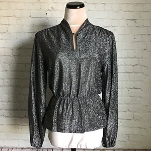 May include: A silver and black long-sleeved blouse with a high neckline and a cinched waist.