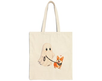 May include: A beige canvas tote bag featuring a printed illustration of a white ghost holding a black leash attached to a brown and white Corgi dog wearing a black bandana. A small red heart is positioned above the dog's head.