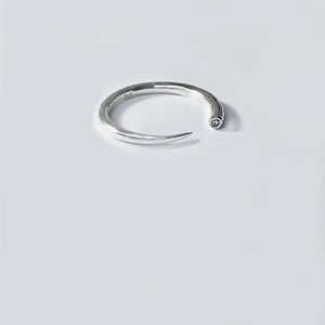 May include: A silver ring with a pointed end and a small diamond set into the metal.