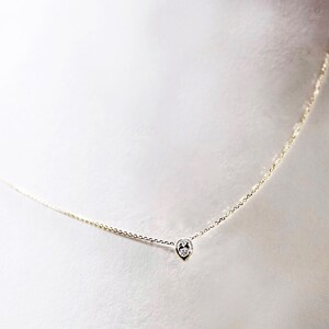 May include: A delicate gold chain necklace with a single, small, round diamond pendant.