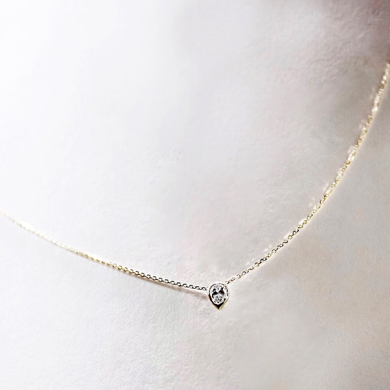 May include: A delicate gold chain necklace with a single, small, round diamond pendant.