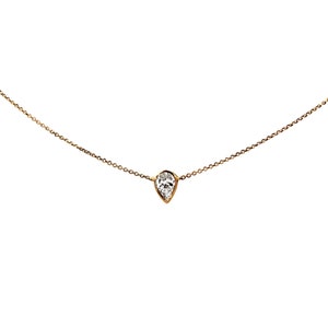 May include: A delicate gold chain necklace with a single pear-shaped diamond pendant.