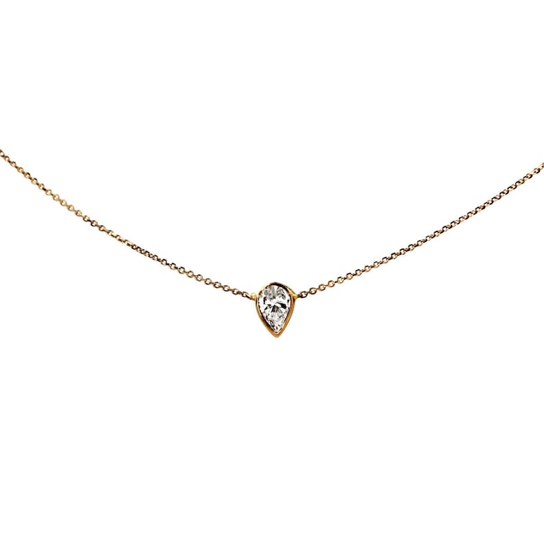 May include: A delicate gold chain necklace with a single pear-shaped diamond pendant.