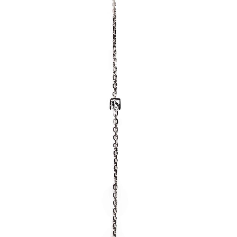May include: A silver chain necklace with a small square pendant featuring a clear crystal.