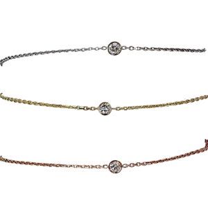 May include: Three delicate necklaces with a single diamond pendant each. The necklaces are in silver, gold, and rose gold.