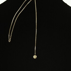 May include: A gold chain necklace with a single clear stone pendant.