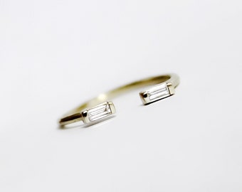 Op de afbeelding: Een gouden ring met twee baguette-vormige diamanten die in de band zijn gezet.