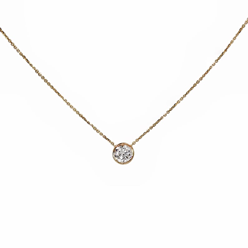 May include: A delicate gold chain necklace with a single round diamond pendant.