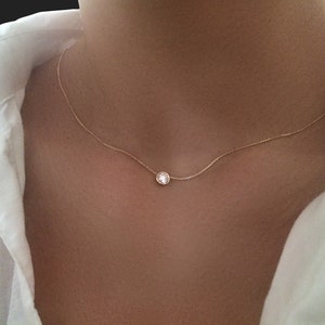 May include: A delicate gold chain necklace with a single round clear stone pendant.