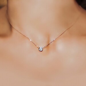 May include: A simple silver chain necklace with a single round diamond pendant.