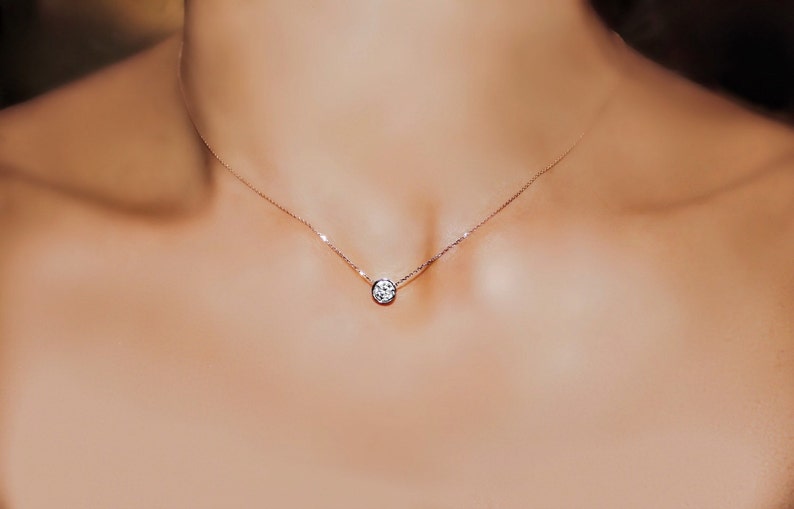 May include: A simple silver chain necklace with a single round diamond pendant.