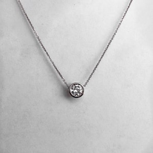 May include: A silver chain necklace with a round, bezel-set diamond pendant.