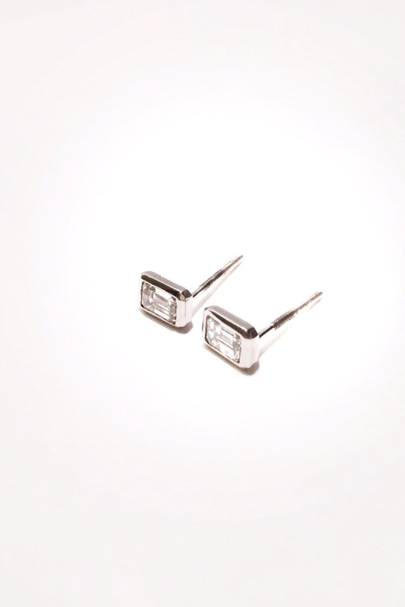 Puede incluir: Un par de pendientes de plata con piedras preciosas rectangulares transparentes.