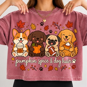 Peut inclure: Un sweat-shirt à col rond bordeaux délavé avec un motif de quatre chiens de dessin animé tenant une tasse de café, une citrouille, un ballon de football et une part de tarte, entourés de feuilles d'automne et du texte pumpkin spice & dog hair.