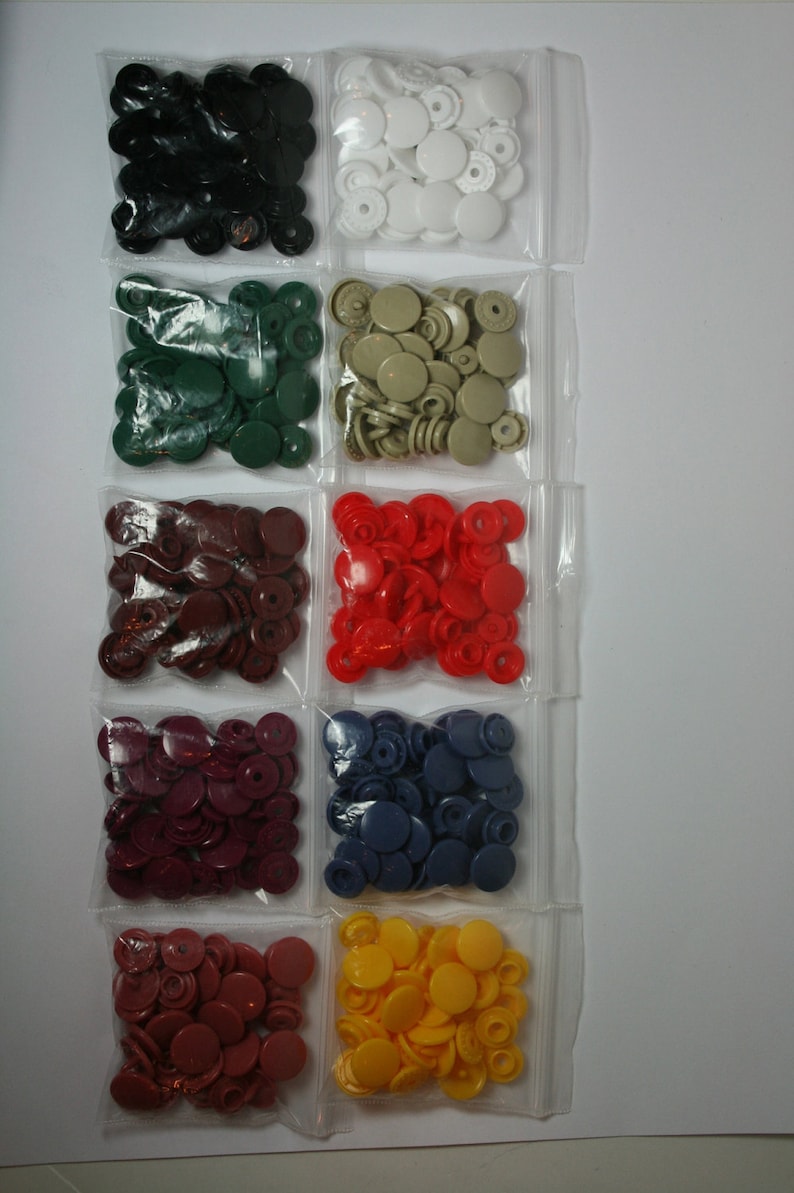 May include: Assortment of plastic snap buttons in various colors, including black, white, green, red, burgundy, blue, and yellow. The buttons are packaged in individual clear plastic bags.