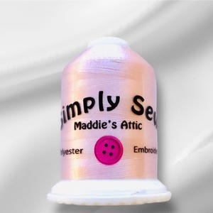 May include: A spool of iridescent pink polyester embroidery thread with the text "Simply Sew Maddie's Attic" and a pink button with four holes.