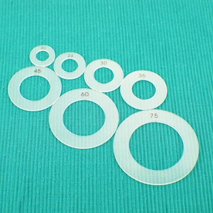 May include: Set of seven clear plastic circles with different sizes marked with numbers: 20, 24, 30, 36, 45, 60, and 75.