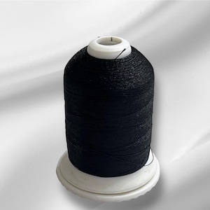 May include: A spool of black thread on a white bobbin.