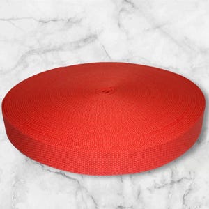 May include: A roll of bright red webbing, a type of heavy-duty fabric used for straps, belts, and other applications.