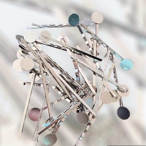 Peut inclure: Un tas de pinces à cheveux argentées avec des accents métalliques ronds et colorés. Les accents sont dans des tons de bleu, vert et marron.