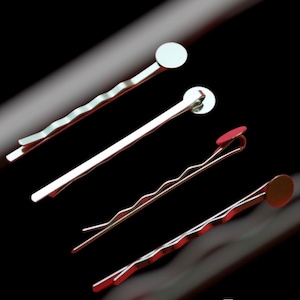 Op de afbeelding: Vier zilveren haarclips met verschillende ronde versieringen in verschillende kleuren. De versieringen zijn rood, wit en zilver.
