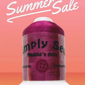 Peut inclure: Une bobine de fil à broder de couleur violette avec le texte "Simply Sew Maddie's Attic" et un bouton sur l'étiquette. Le fil est destiné aux projets de couture et de broderie.