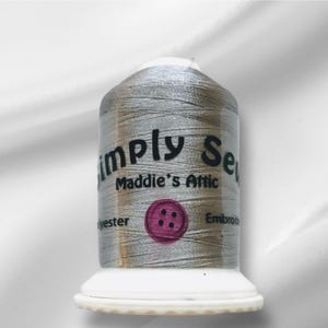 Peut inclure: Une bobine de fil à broder argenté avec une étiquette qui indique "Simply Sew Maddie's Attic" et "Polyester Embroidery Thread".
