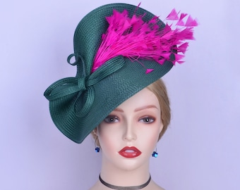 May include: A green and pink hat with a large bow and feathers. The hat is tilted at an angle and has a wide brim.